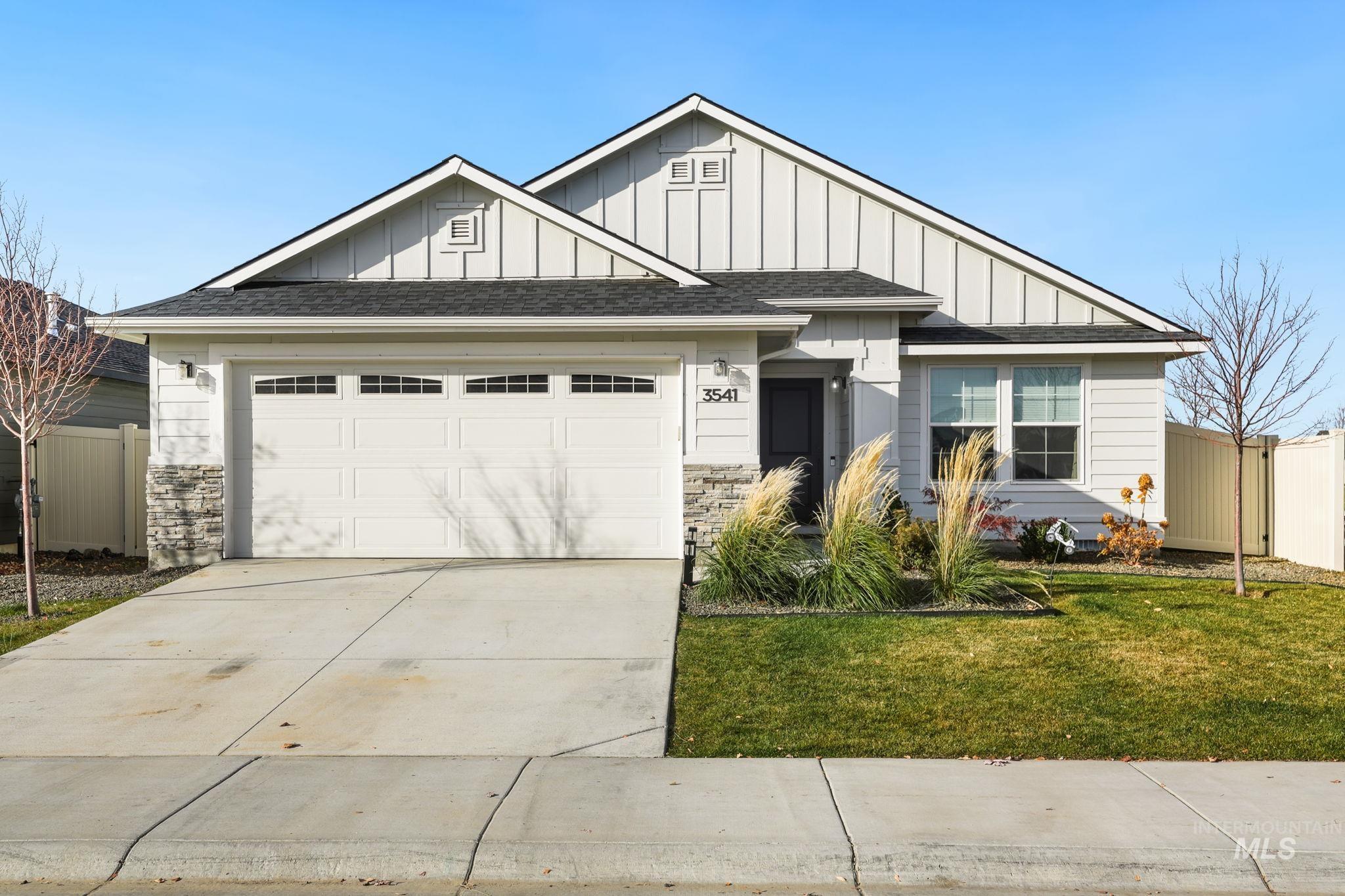 View of front of property with board and batten siding, roof with shingles, concrete driveway, and an attached garage