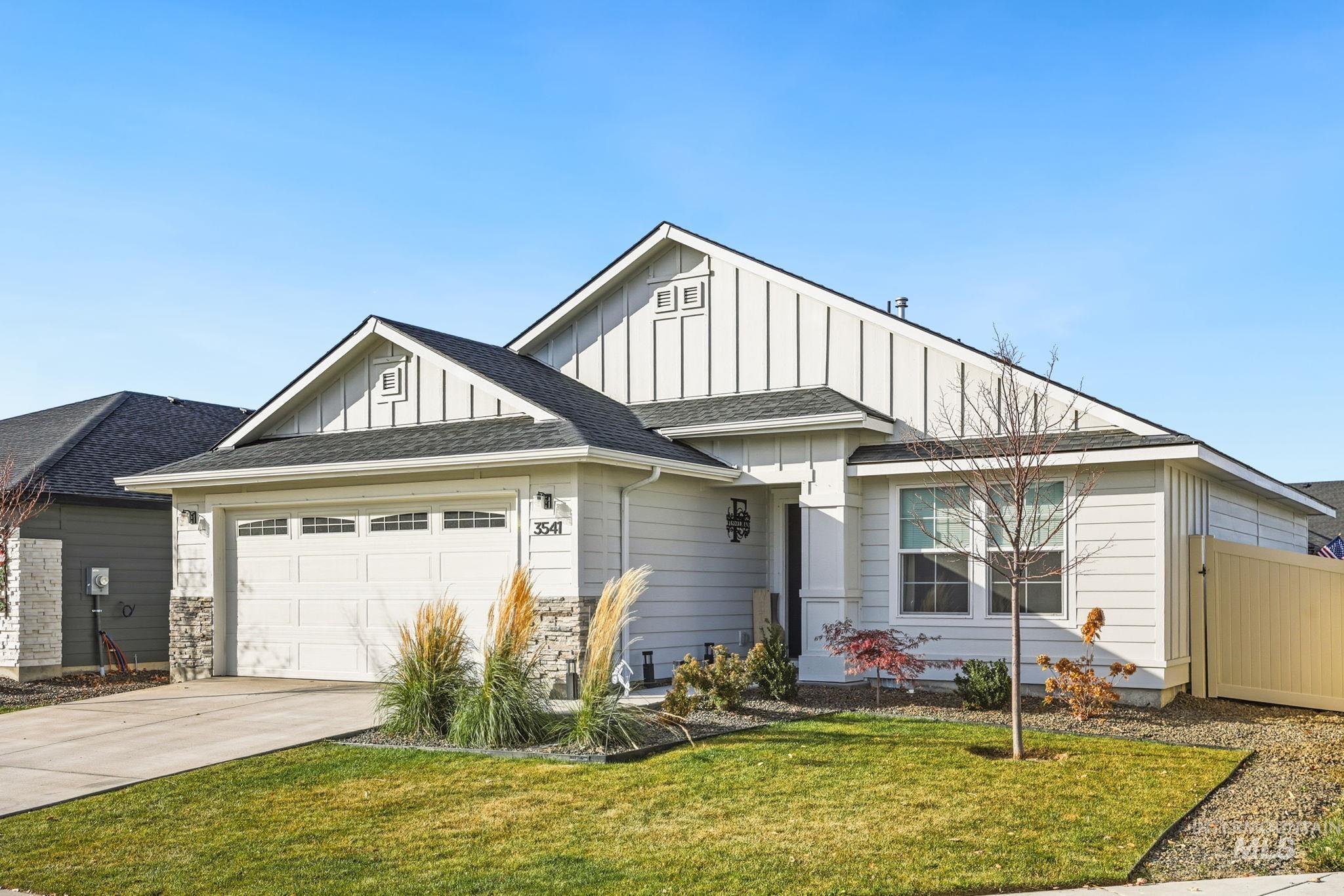 View of front facade featuring board and batten siding, a shingled roof, an attached garage, and driveway