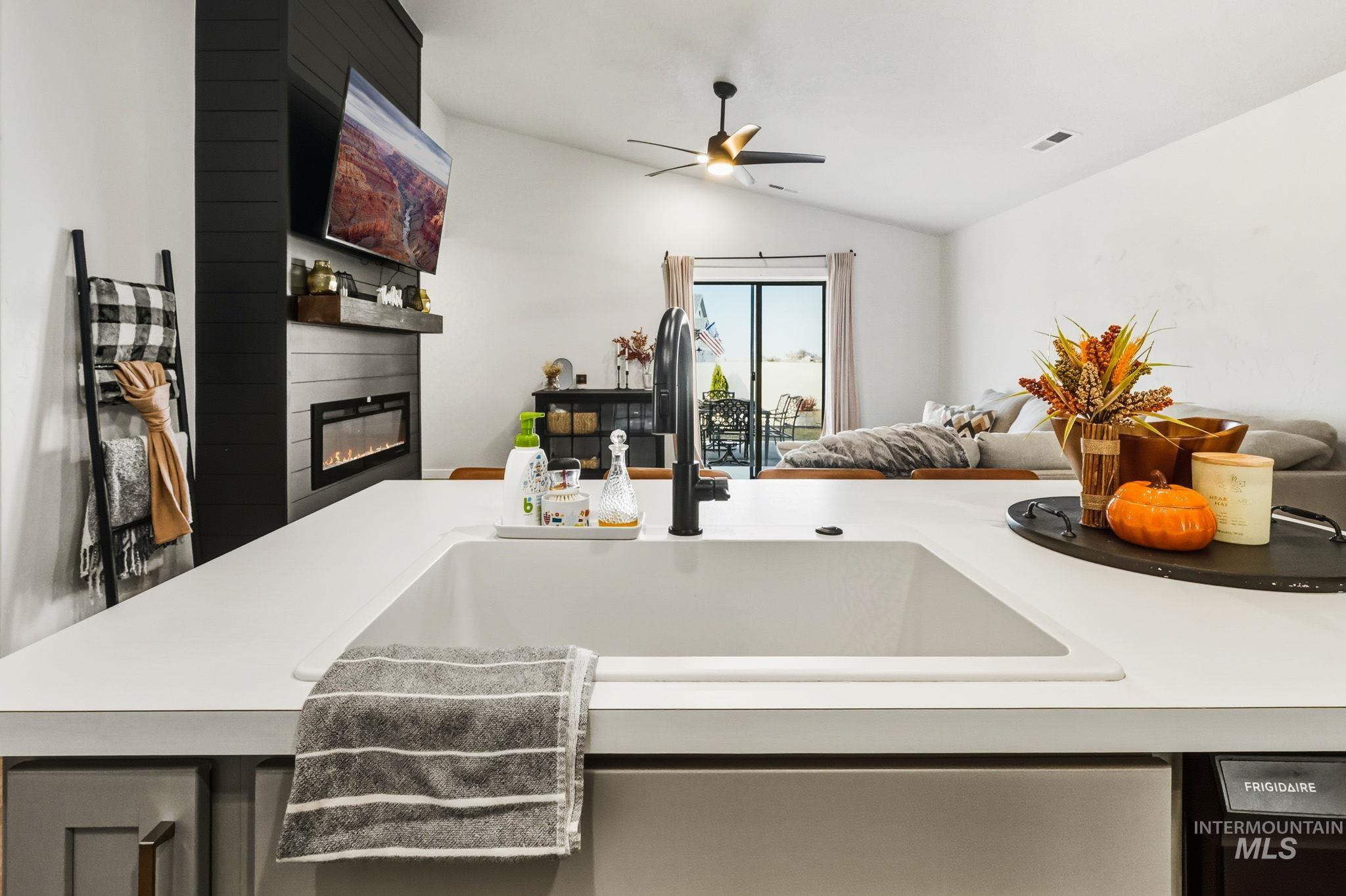 Kitchen with light countertops, a large fireplace, open floor plan, lofted ceiling, and ceiling fan