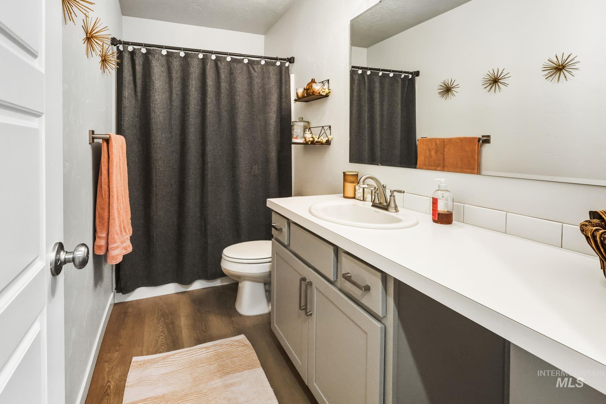 Bathroom with a shower with curtain, dark wood-style flooring, and vanity