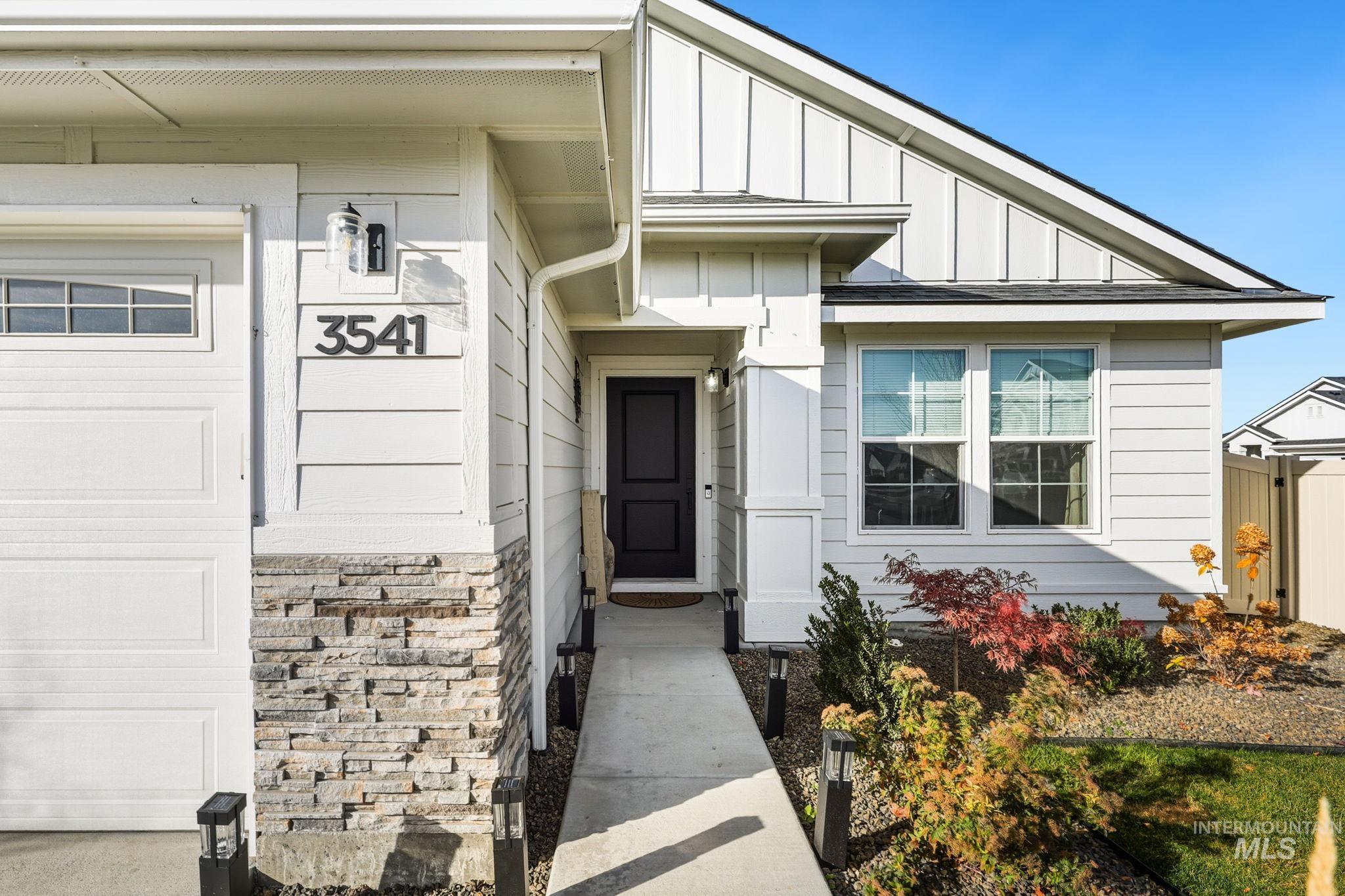Doorway to property featuring board and batten siding, stone siding, and a garage
