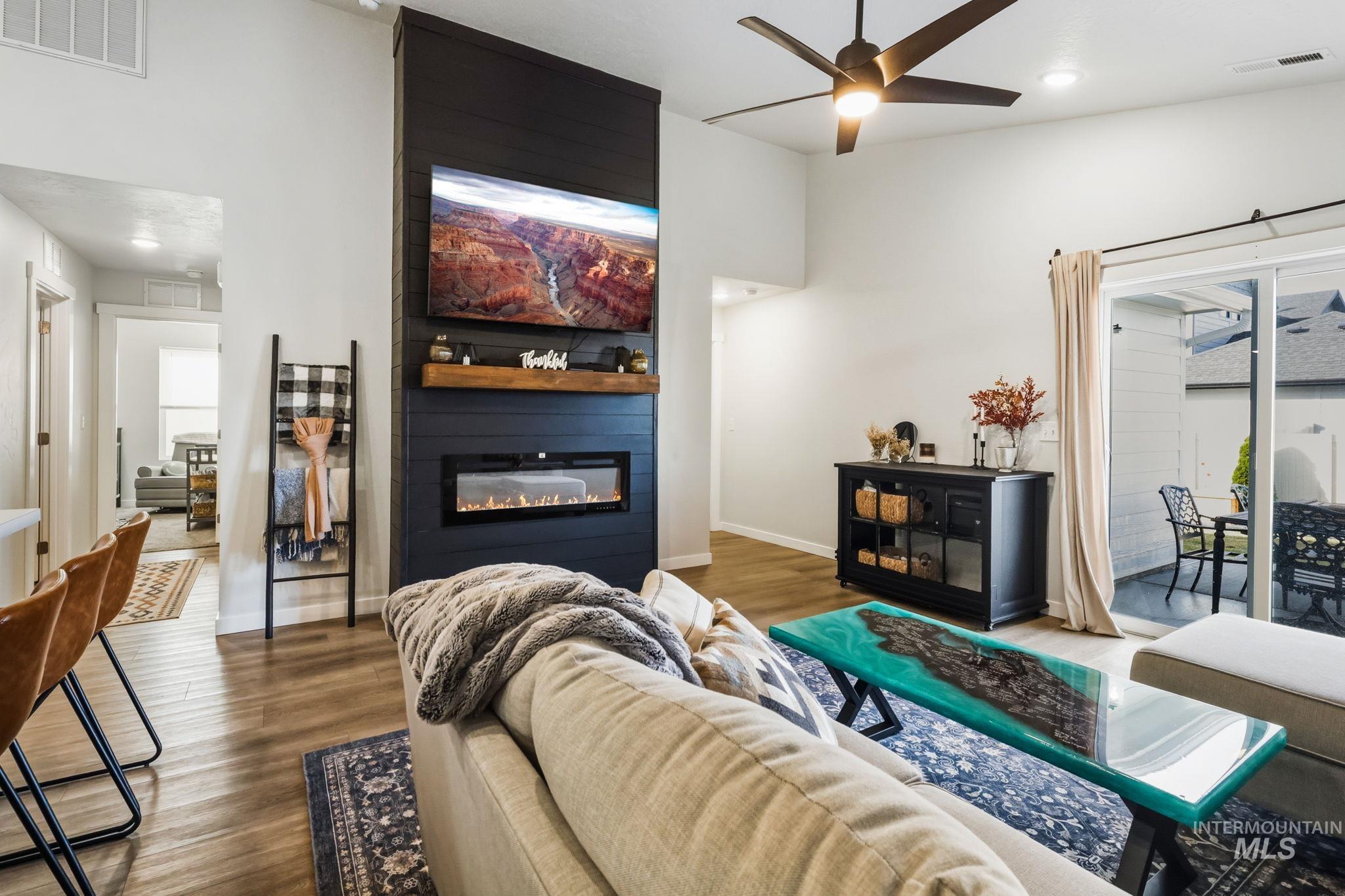 Living room with wood finished floors, a fireplace, ceiling fan, and recessed lighting