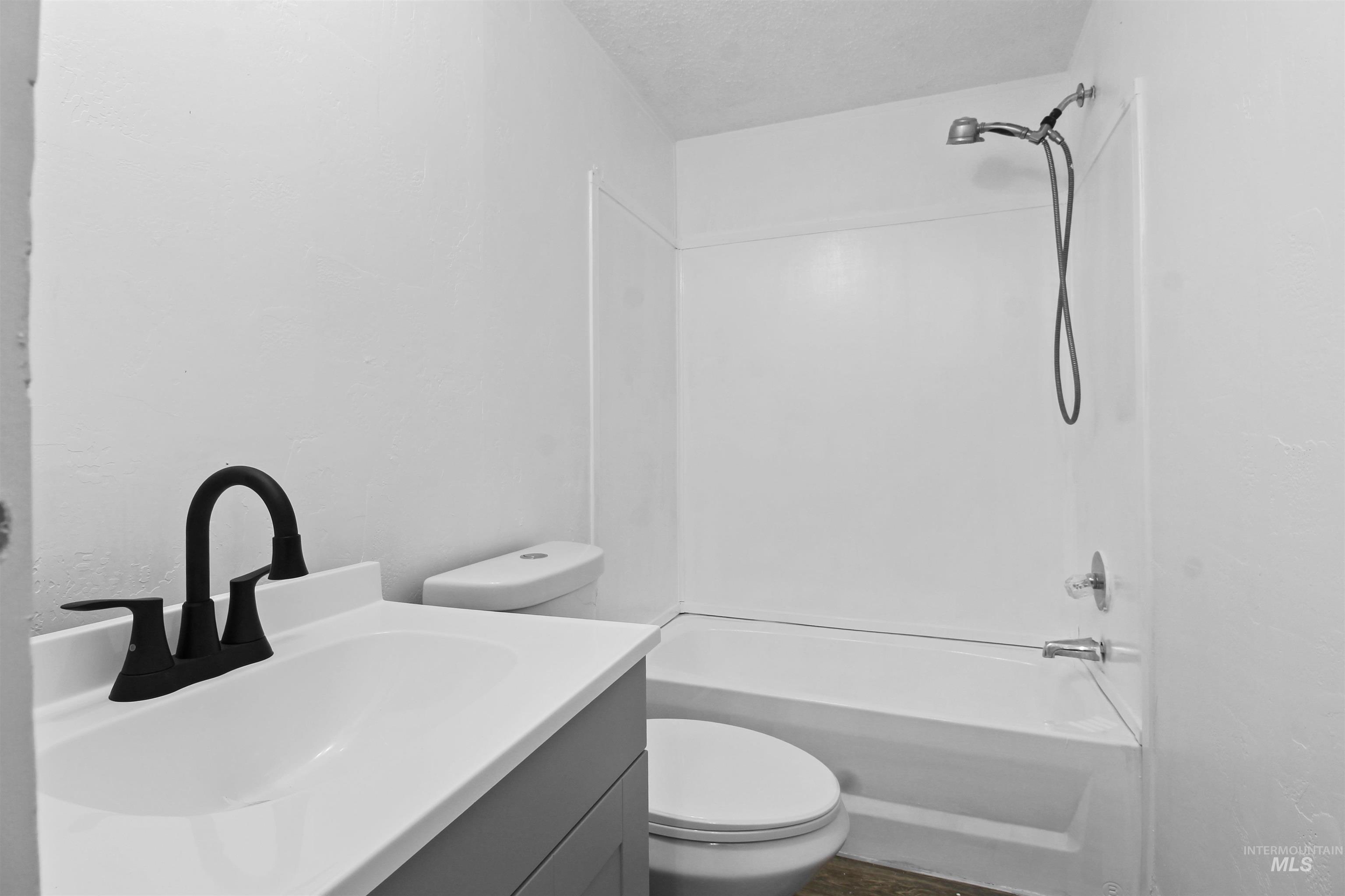 Bathroom featuring tub / shower combination, vanity, and a textured ceiling