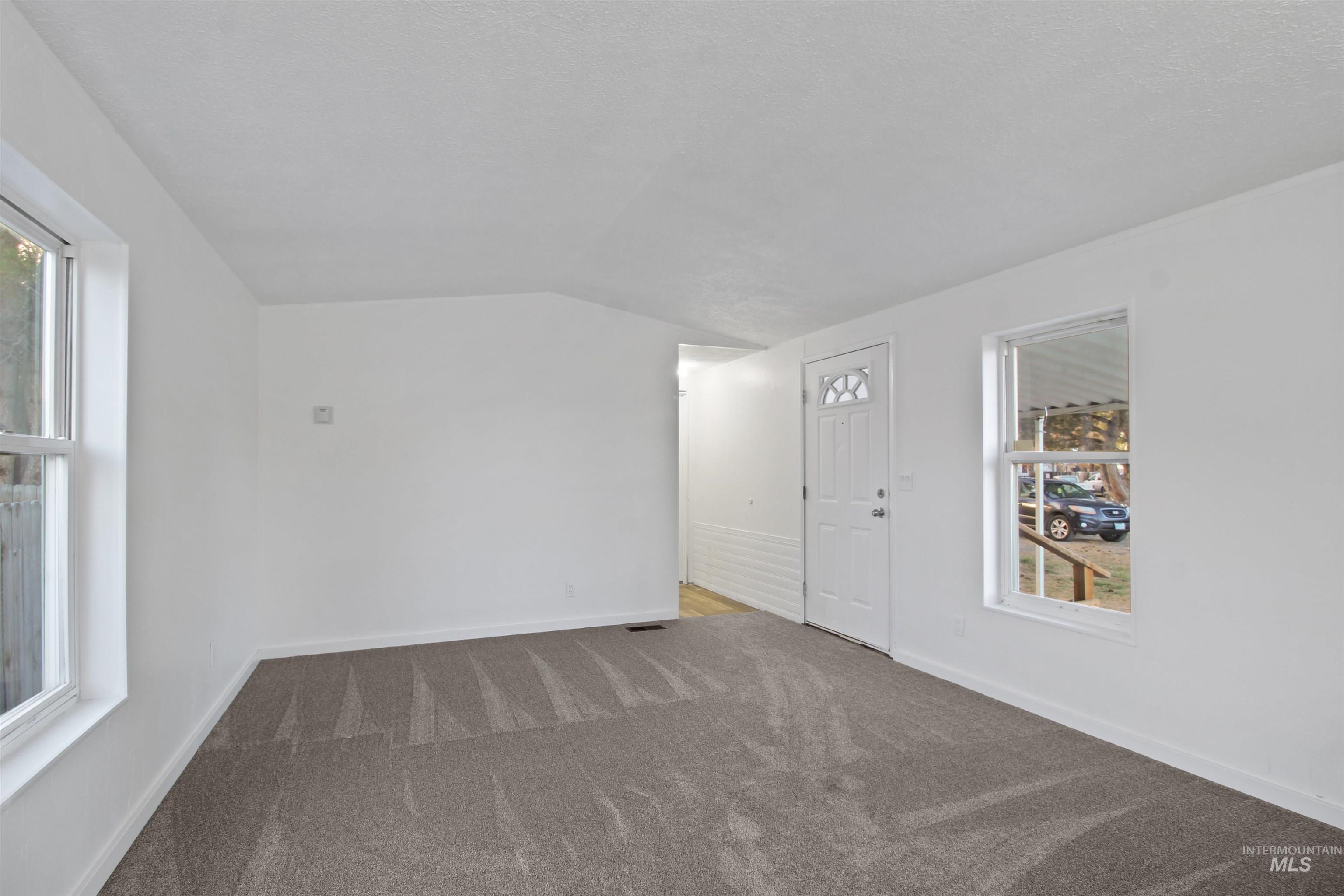 Unfurnished room with carpet floors and lofted ceiling