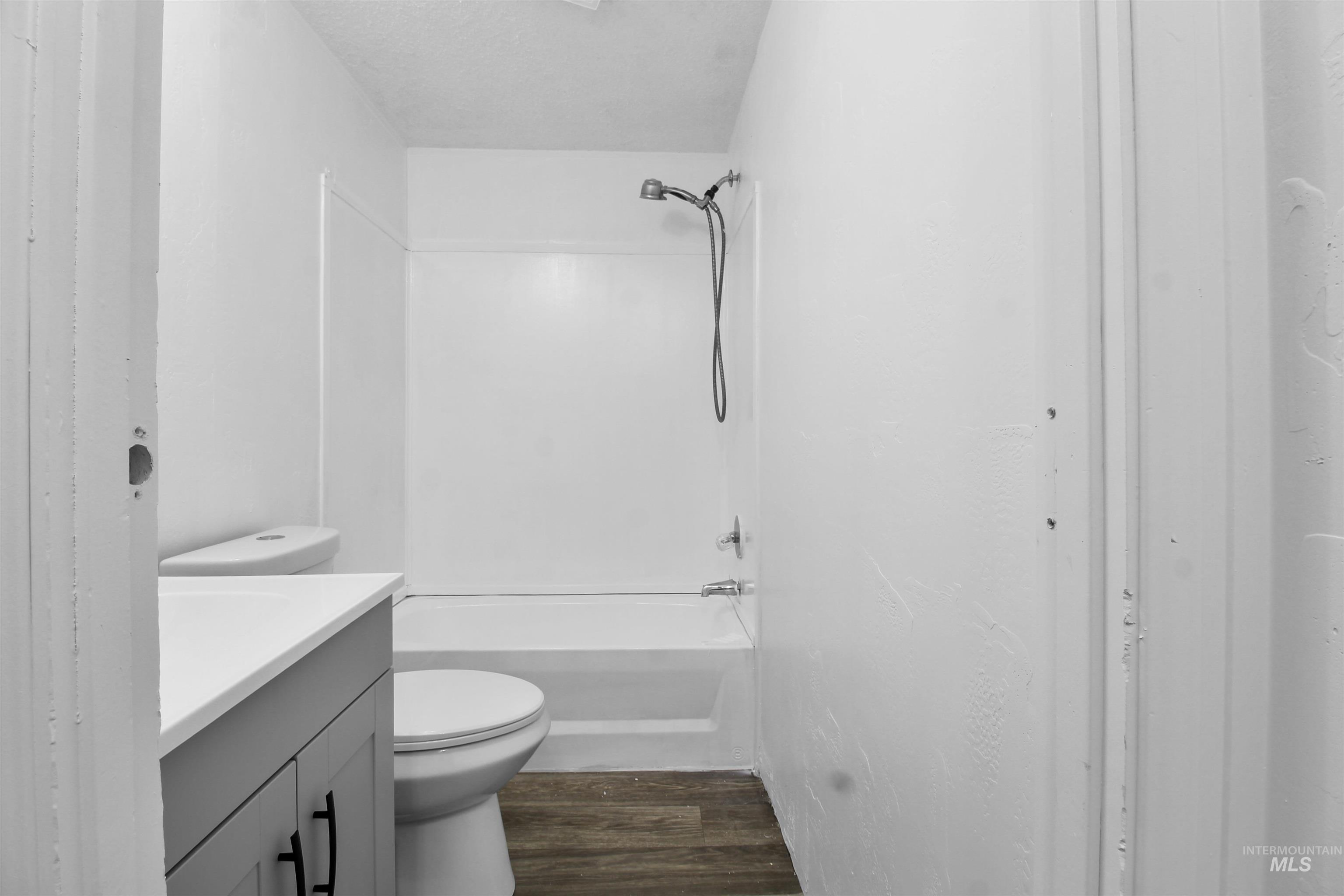 Full bathroom with vanity, shower / washtub combination, dark wood finished floors, and a textured ceiling