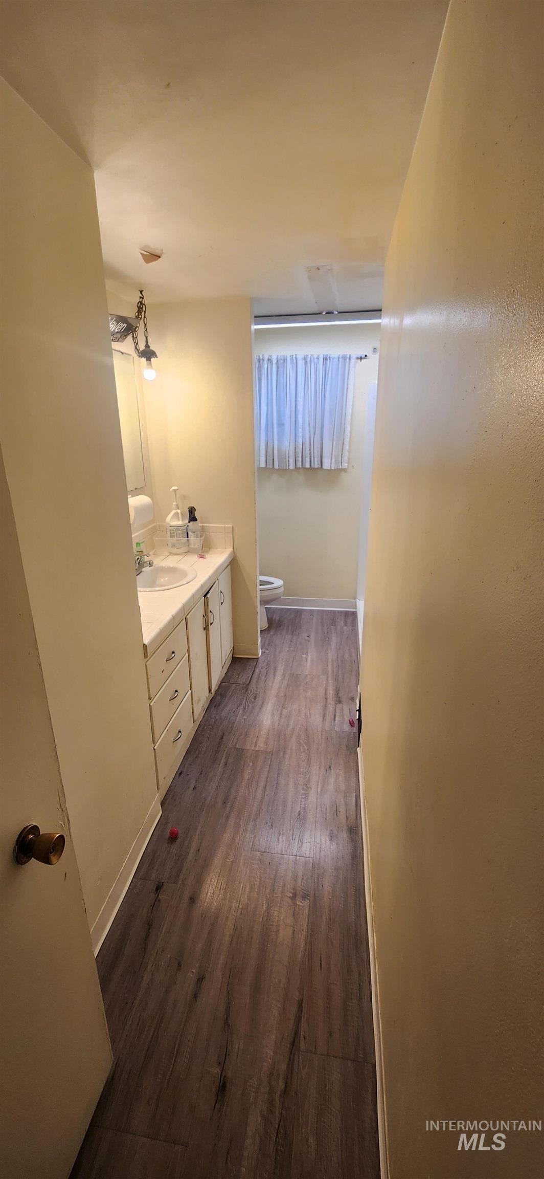 Bathroom with double vanity and dark wood-type flooring