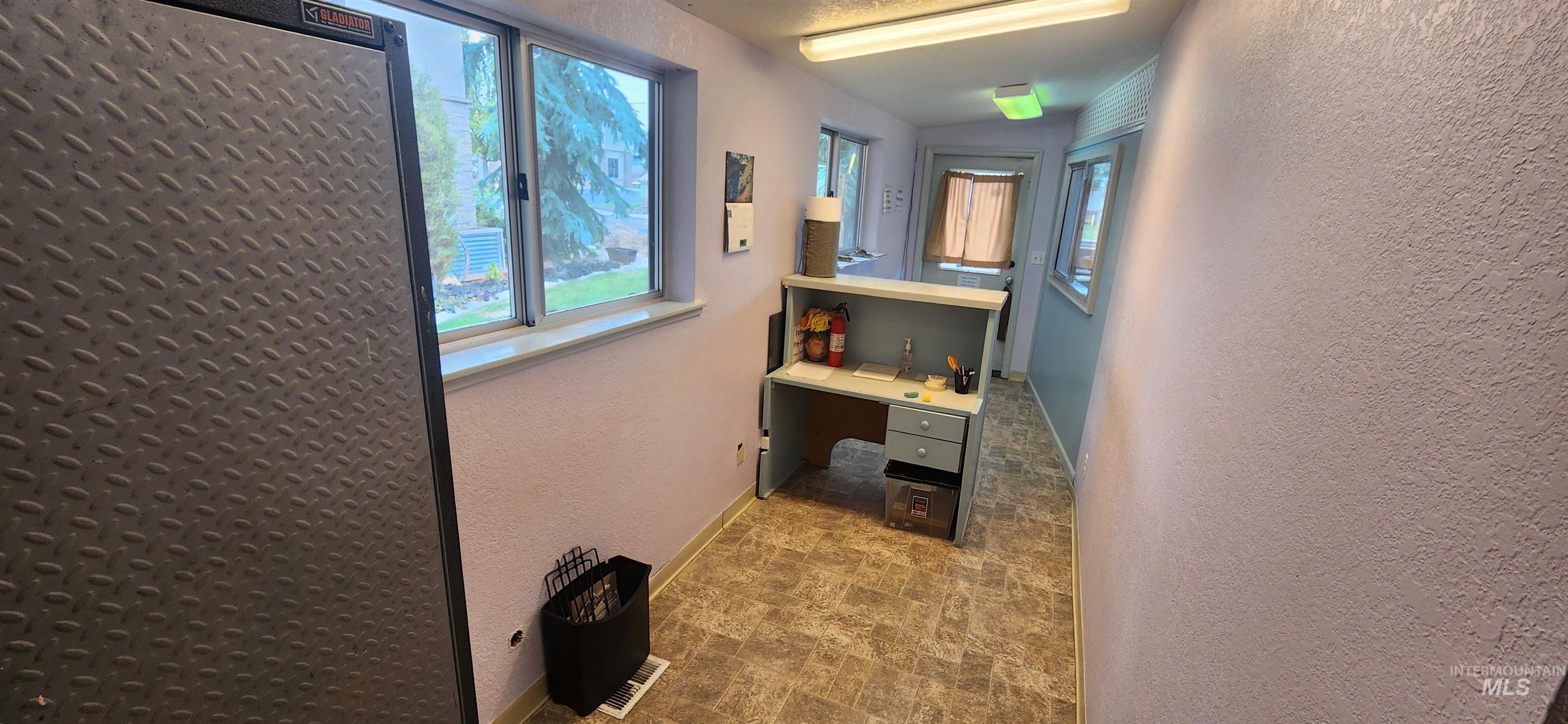 Hall featuring a textured wall and a desk