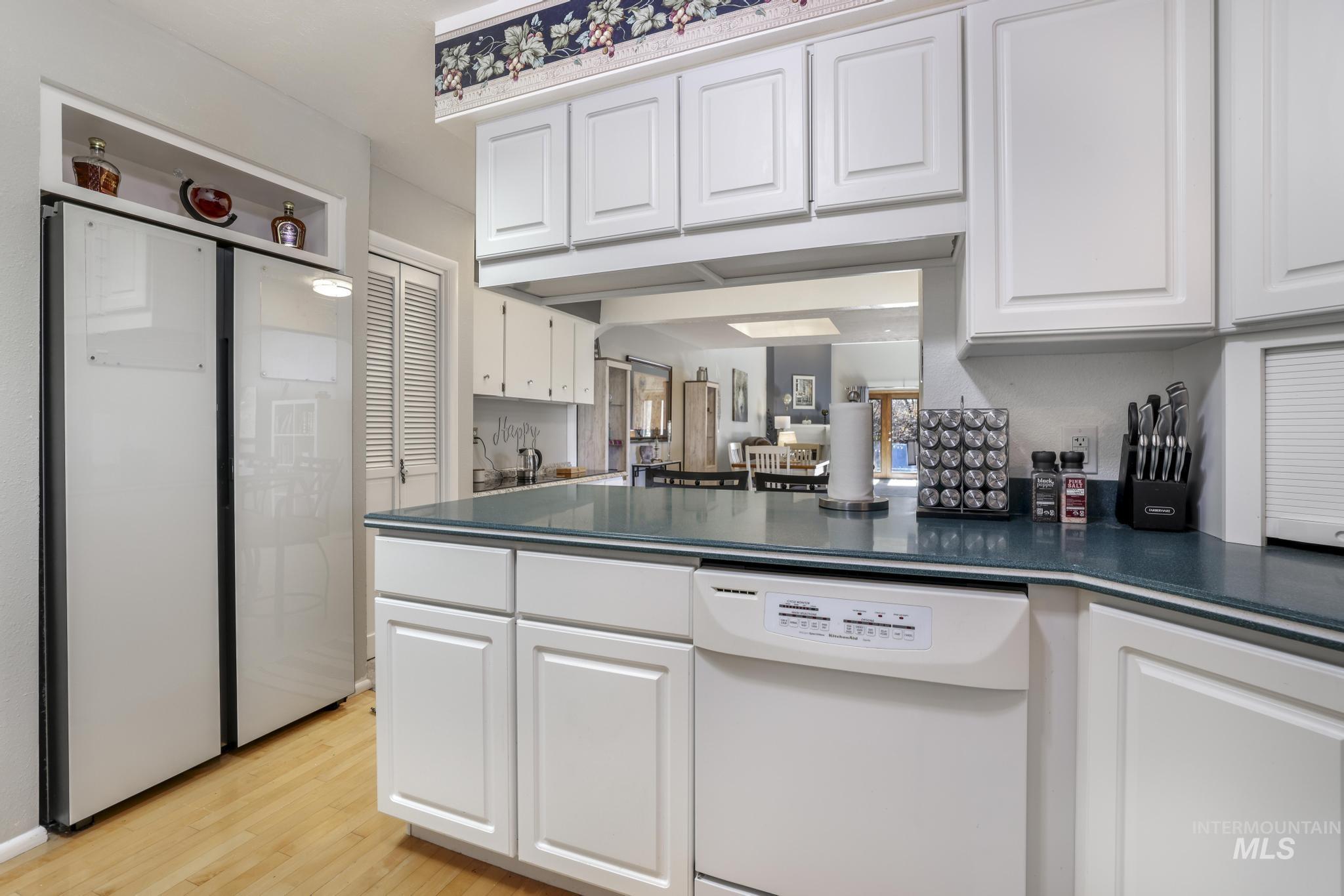 Kitchen featuring white cabinetry, white appliances, light wood-type flooring, and a peninsula