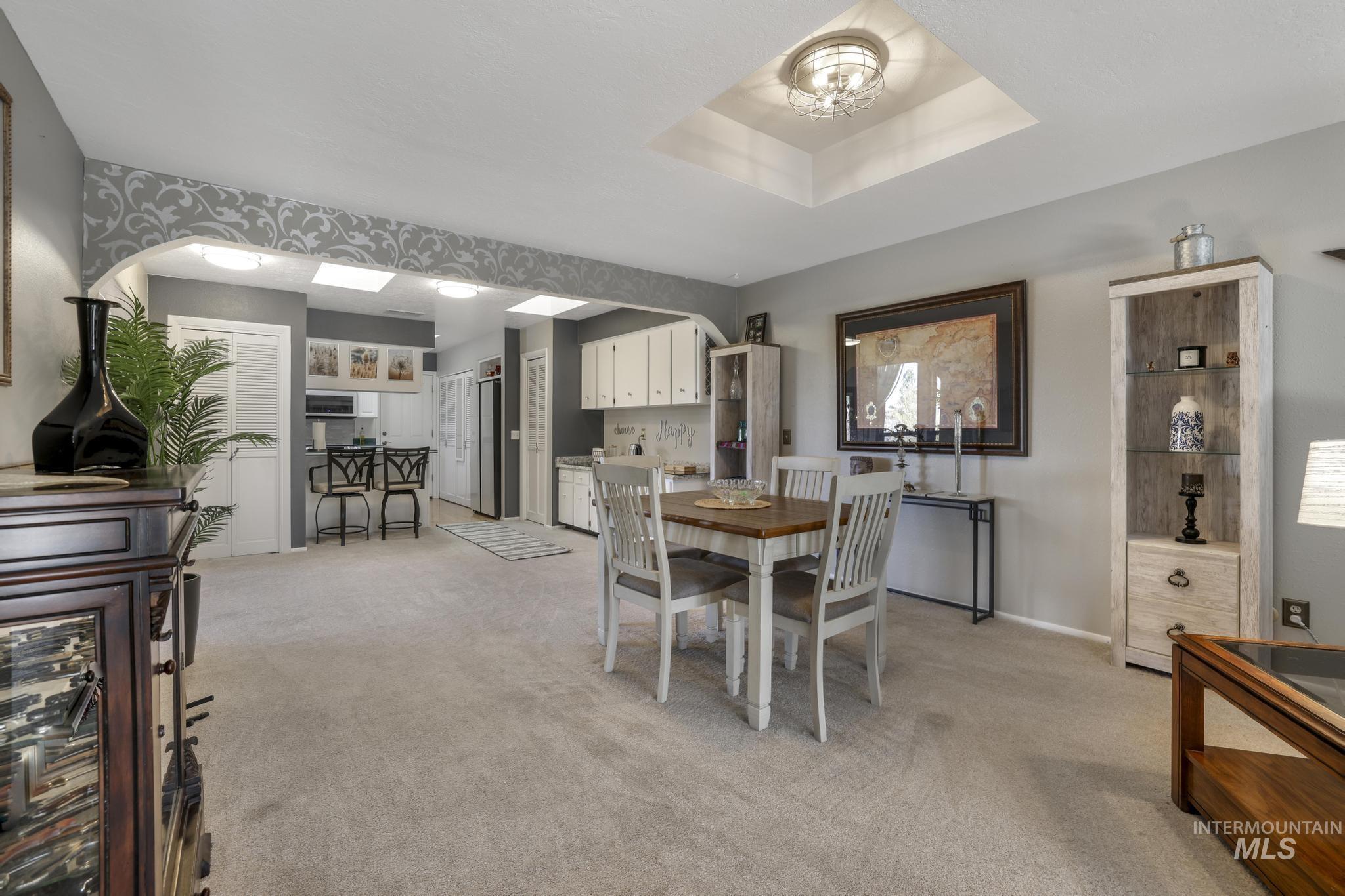 Dining room with light carpet and a tray ceiling