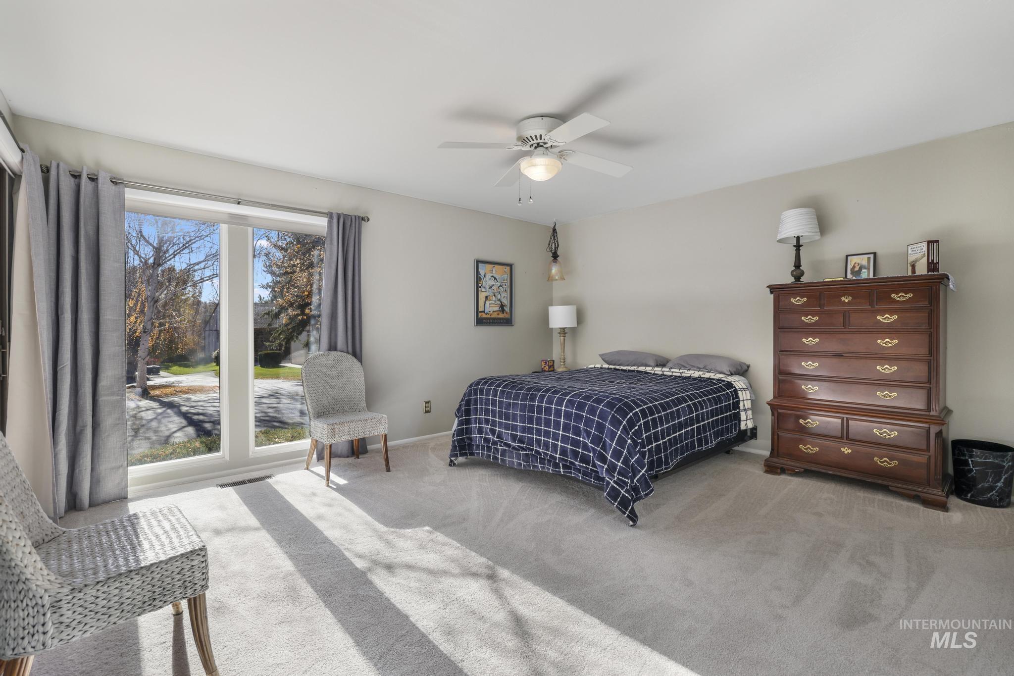Bedroom with light colored carpet and a ceiling fan