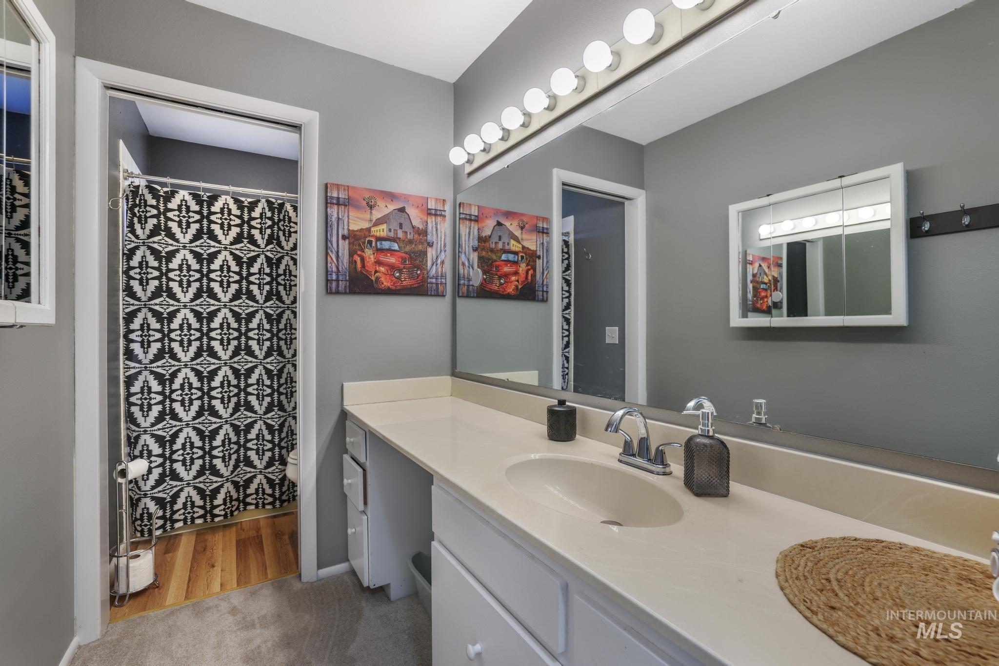 Full bathroom with vanity, a shower with shower curtain, light wood-style floors, and light carpet