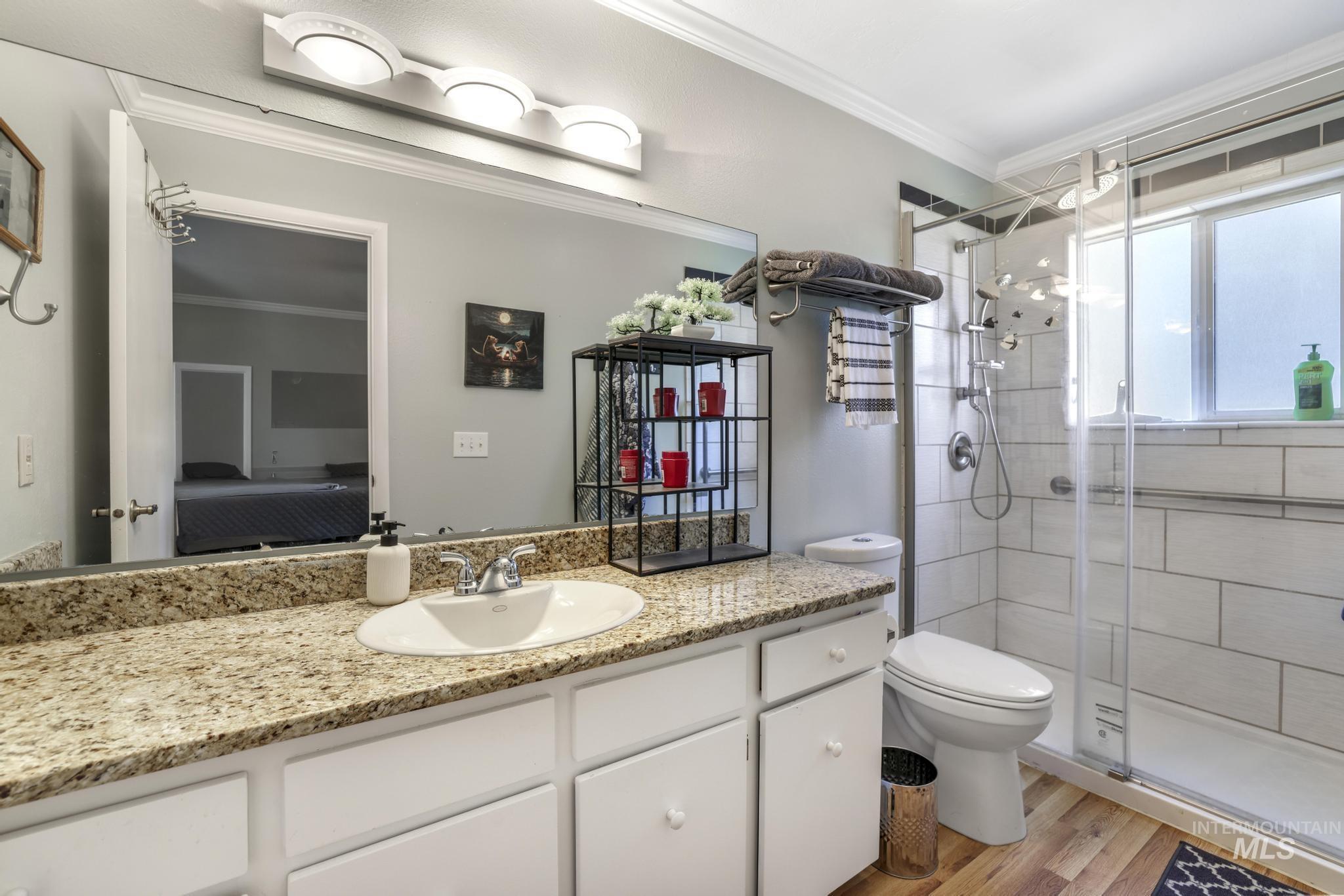 Bathroom with vanity, crown molding, light wood-style floors, ensuite bathroom, and a stall shower