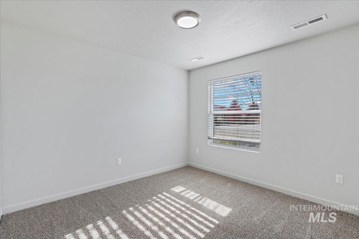Carpeted spare room featuring baseboards and a textured ceiling