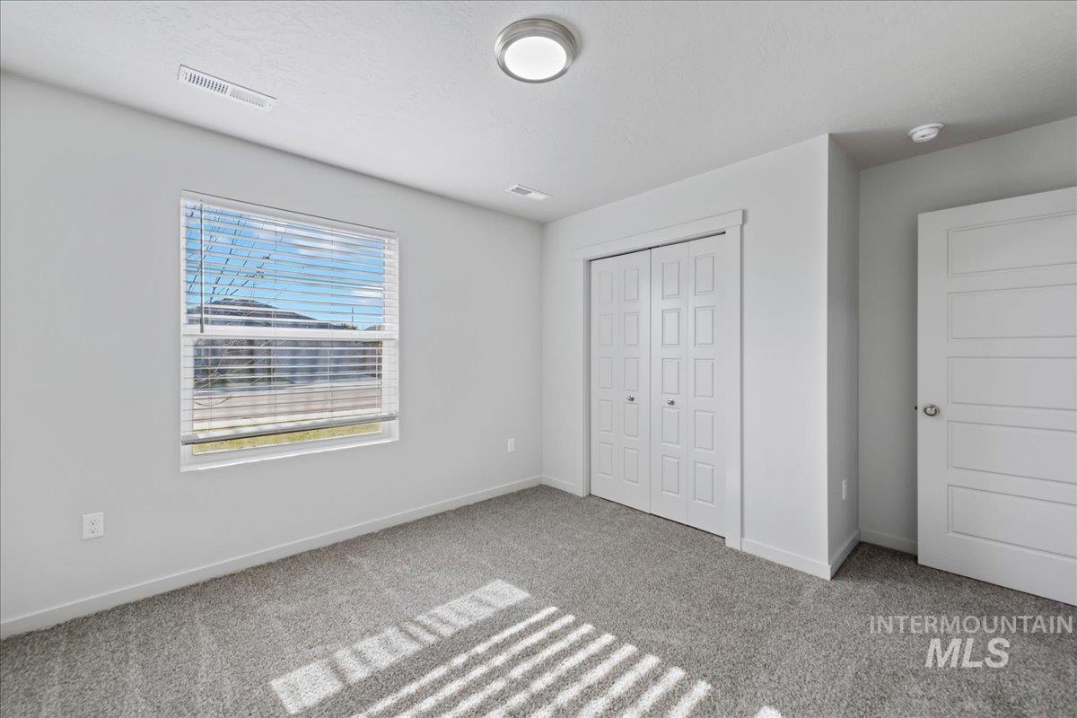 Unfurnished bedroom with light colored carpet and a closet