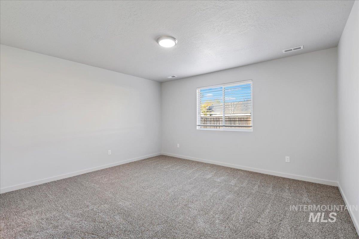 Unfurnished room with light colored carpet and a textured ceiling