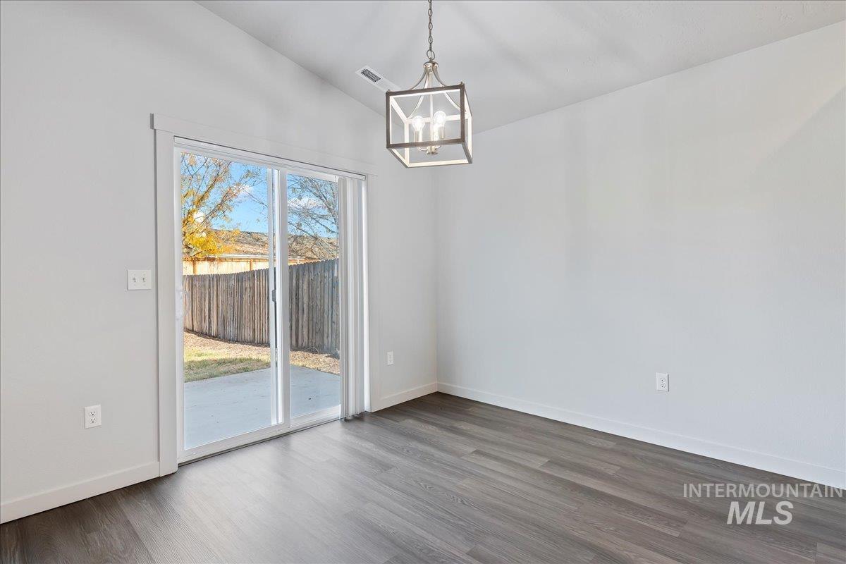 Unfurnished dining area featuring lofted ceiling, dark wood finished floors, and a chandelier
