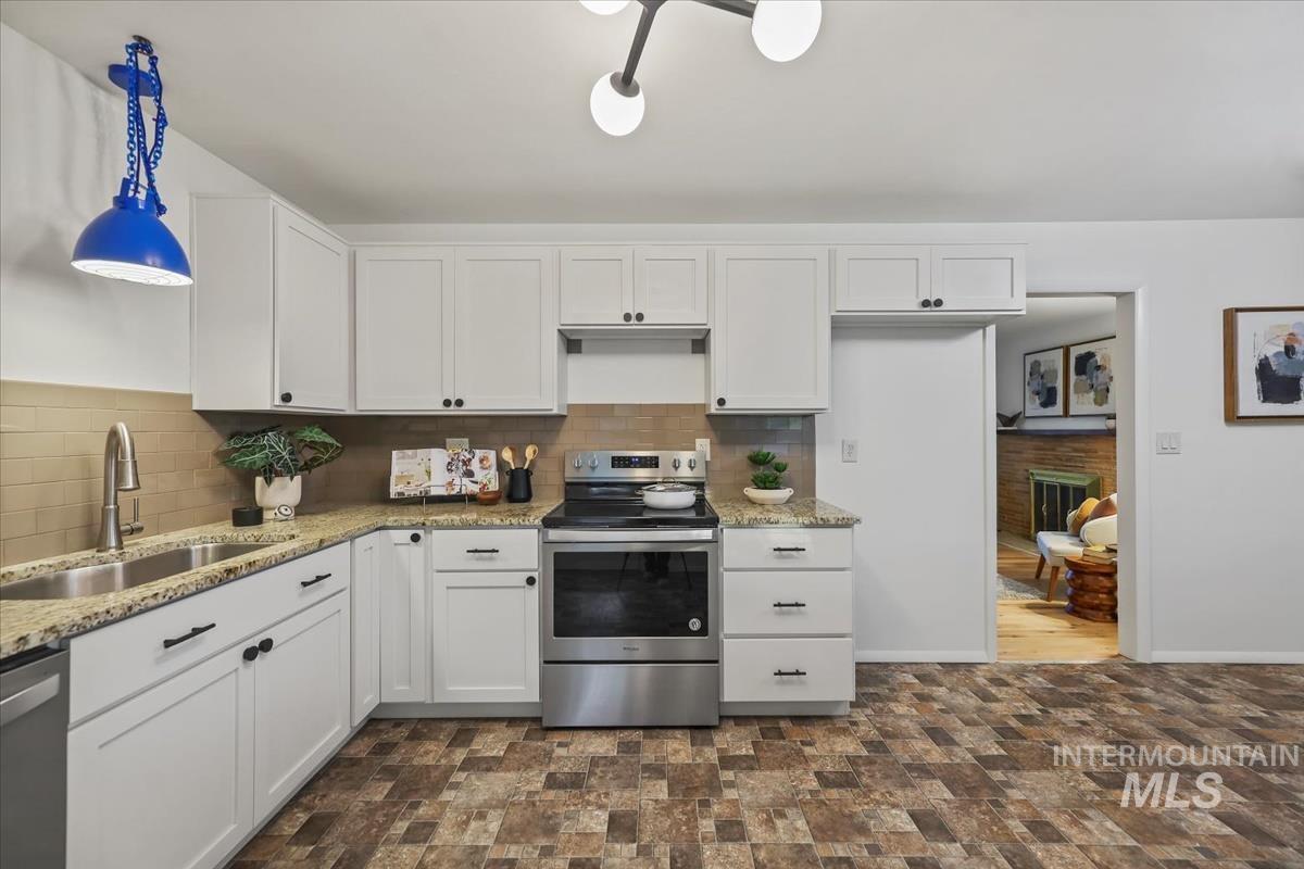 Kitchen with white cabinets, stainless steel appliances, tasteful backsplash, and light stone countertops