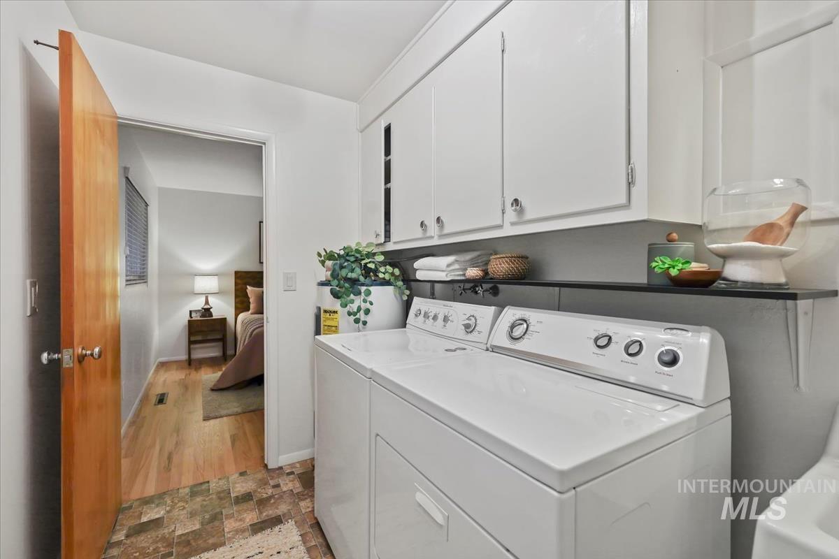 Laundry area featuring cabinet space, washer and dryer, and stone finish floors