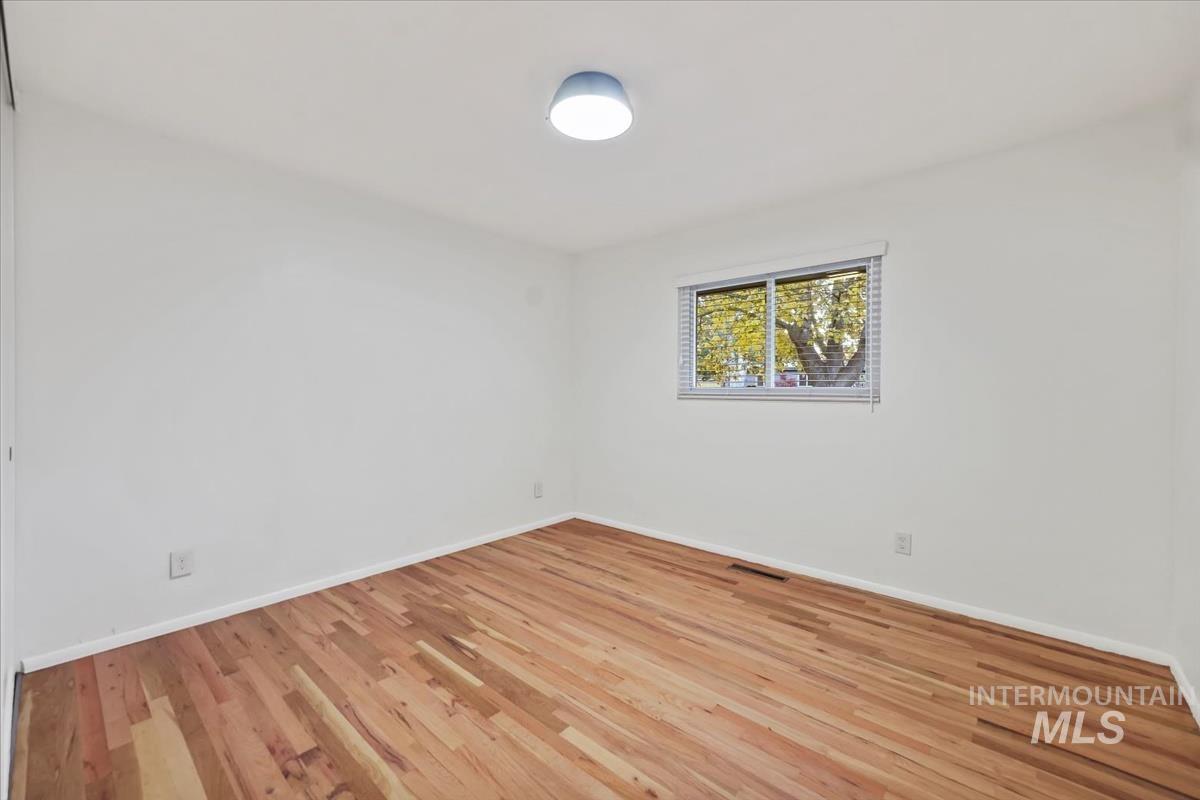 Spare room featuring light wood-type flooring and baseboards