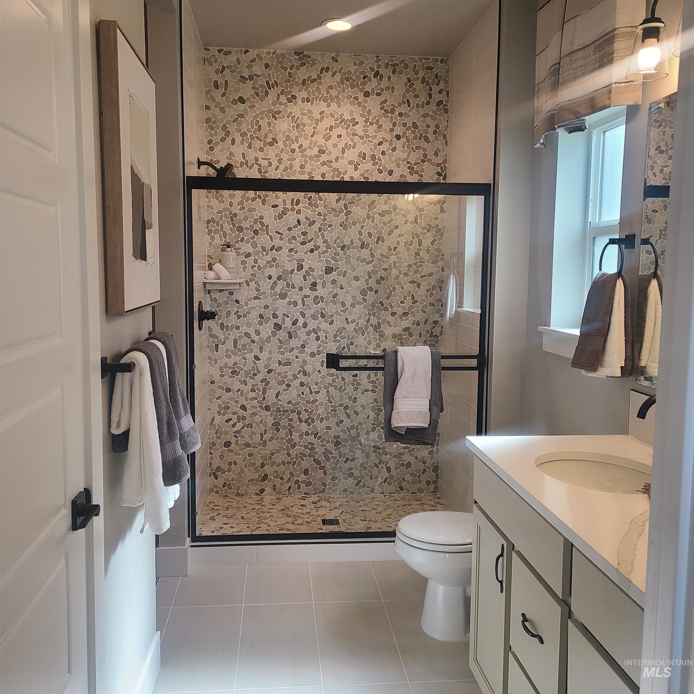 Full bathroom with a stall shower, vanity, and light tile patterned floors