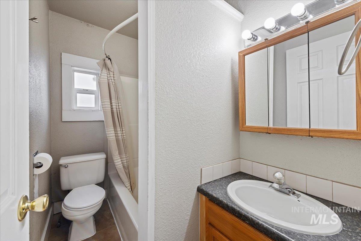Full bathroom with a textured wall, vanity, and shower / bath combo