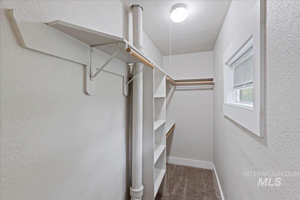 Walk in closet featuring dark carpet