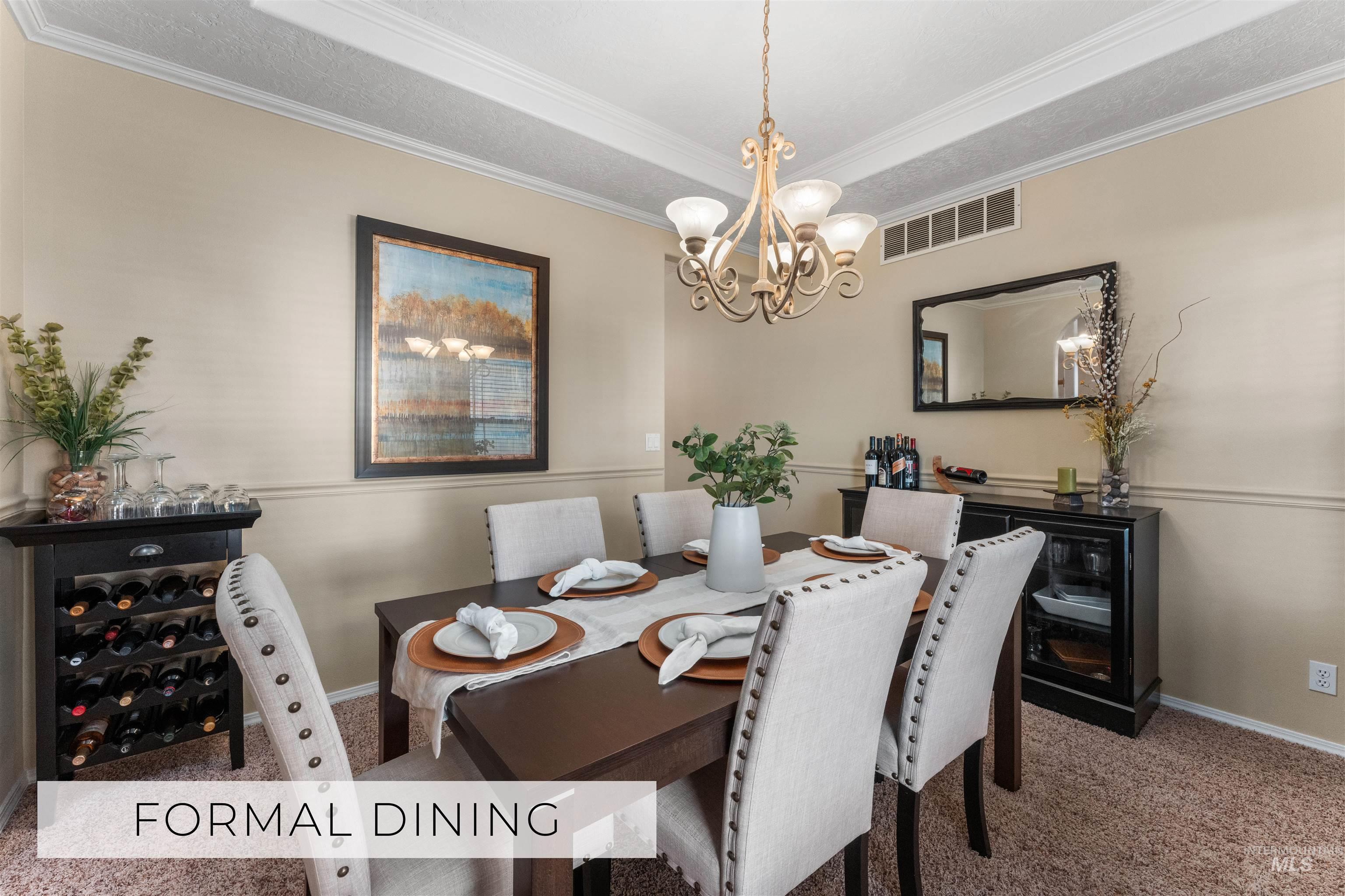 Dining space with carpet flooring, ornamental molding, and a chandelier