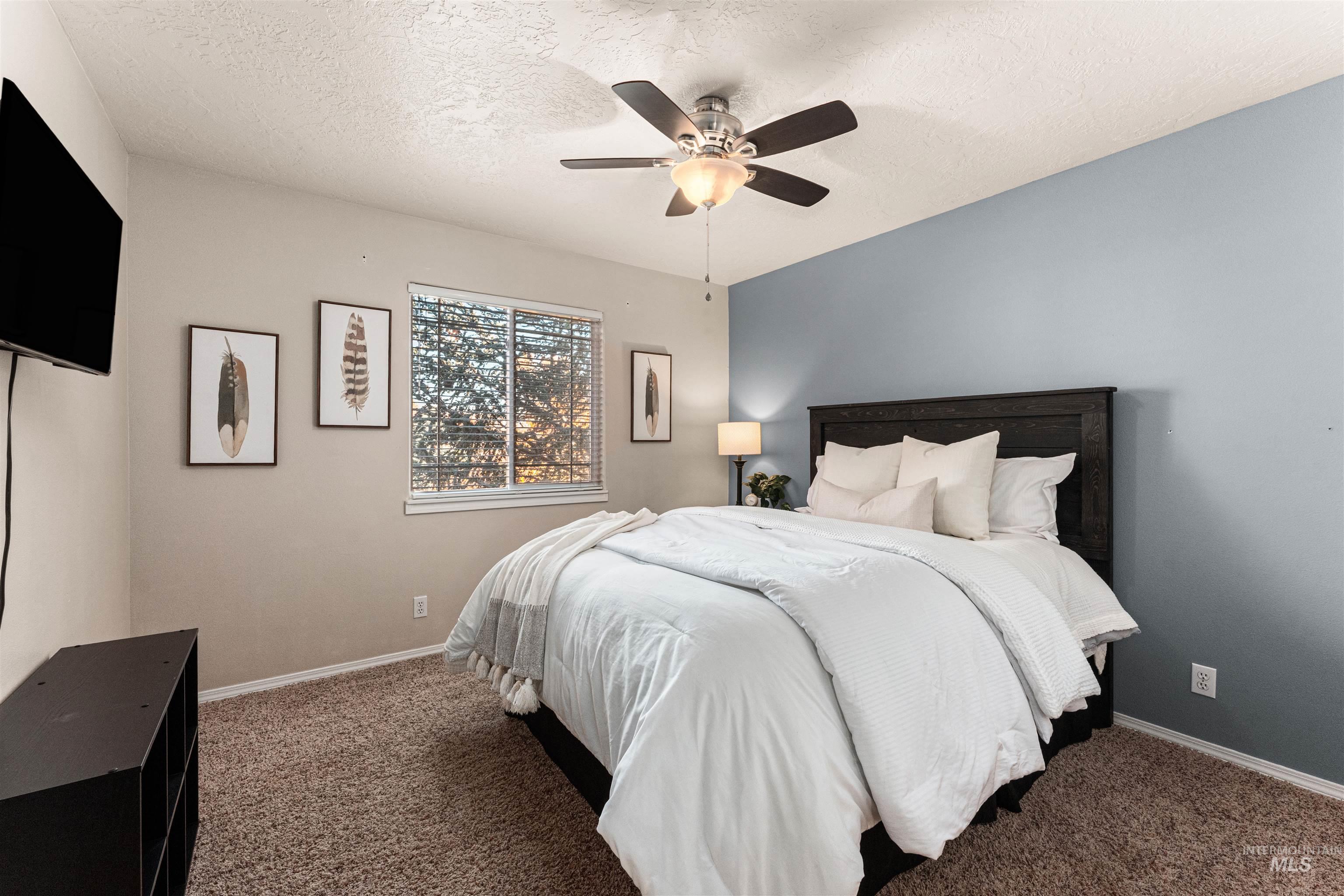 Carpeted bedroom with a textured ceiling and a ceiling fan