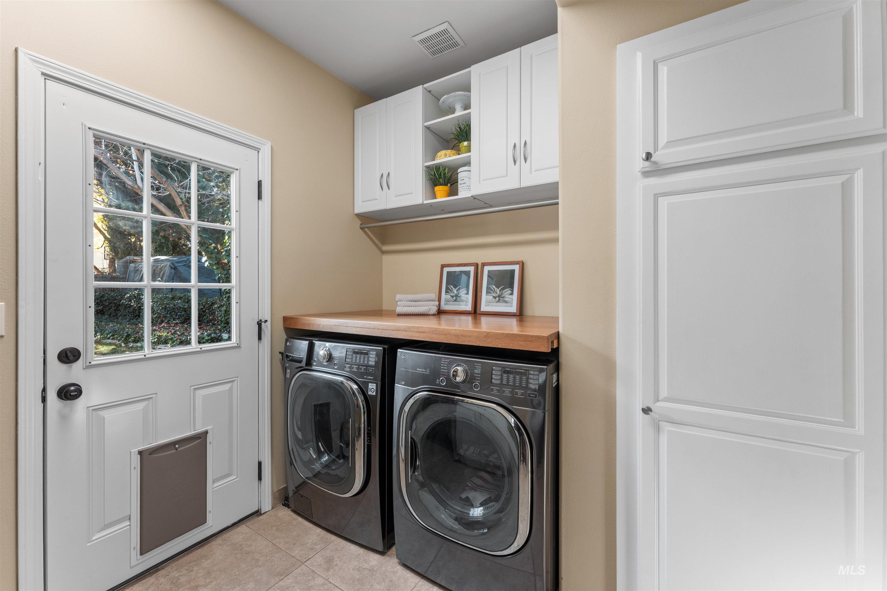 Laundry room featuring washer and dryer, light tile patterned flooring, and cabinet space