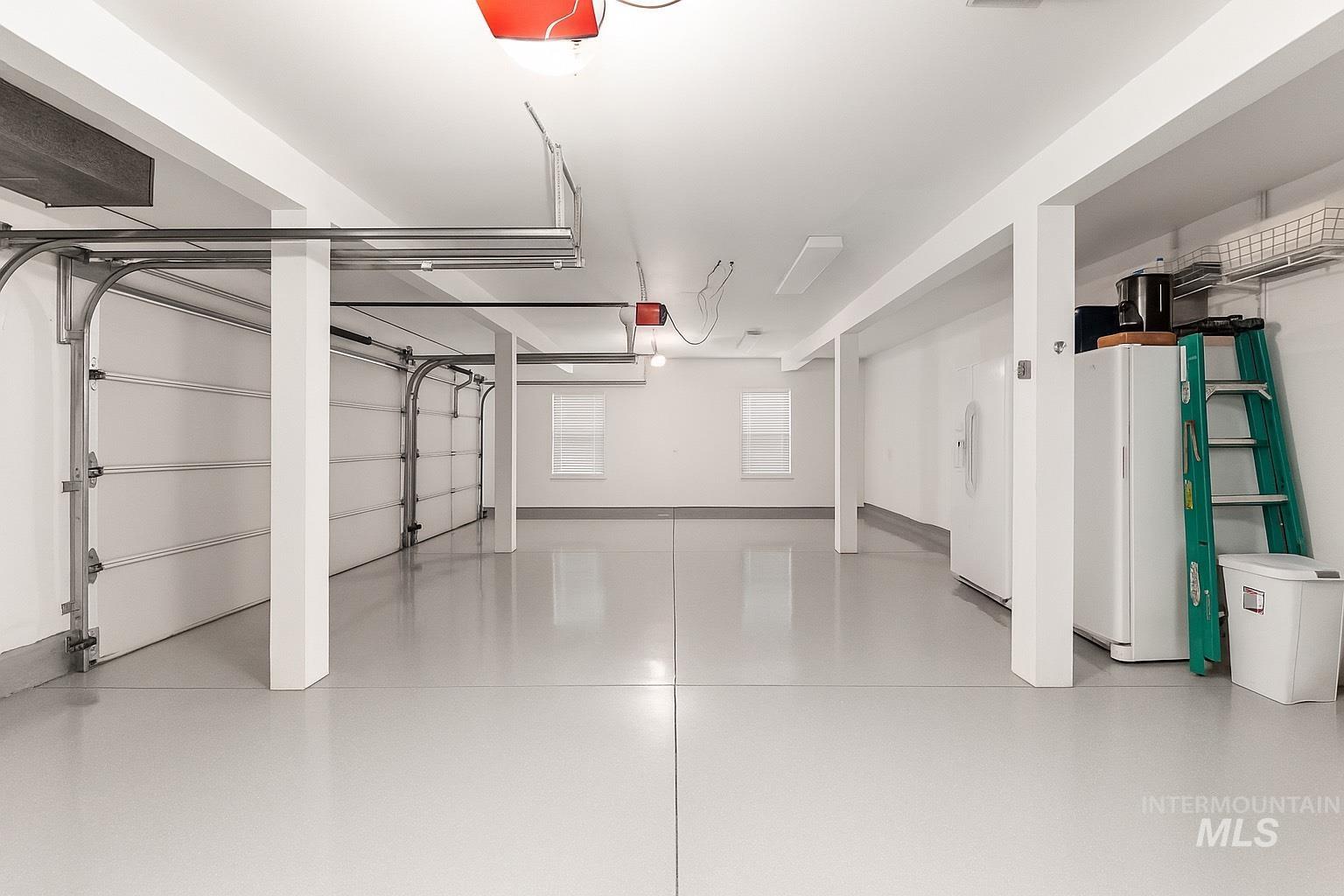 Garage with white fridge with ice dispenser, freestanding refrigerator, and a garage door opener