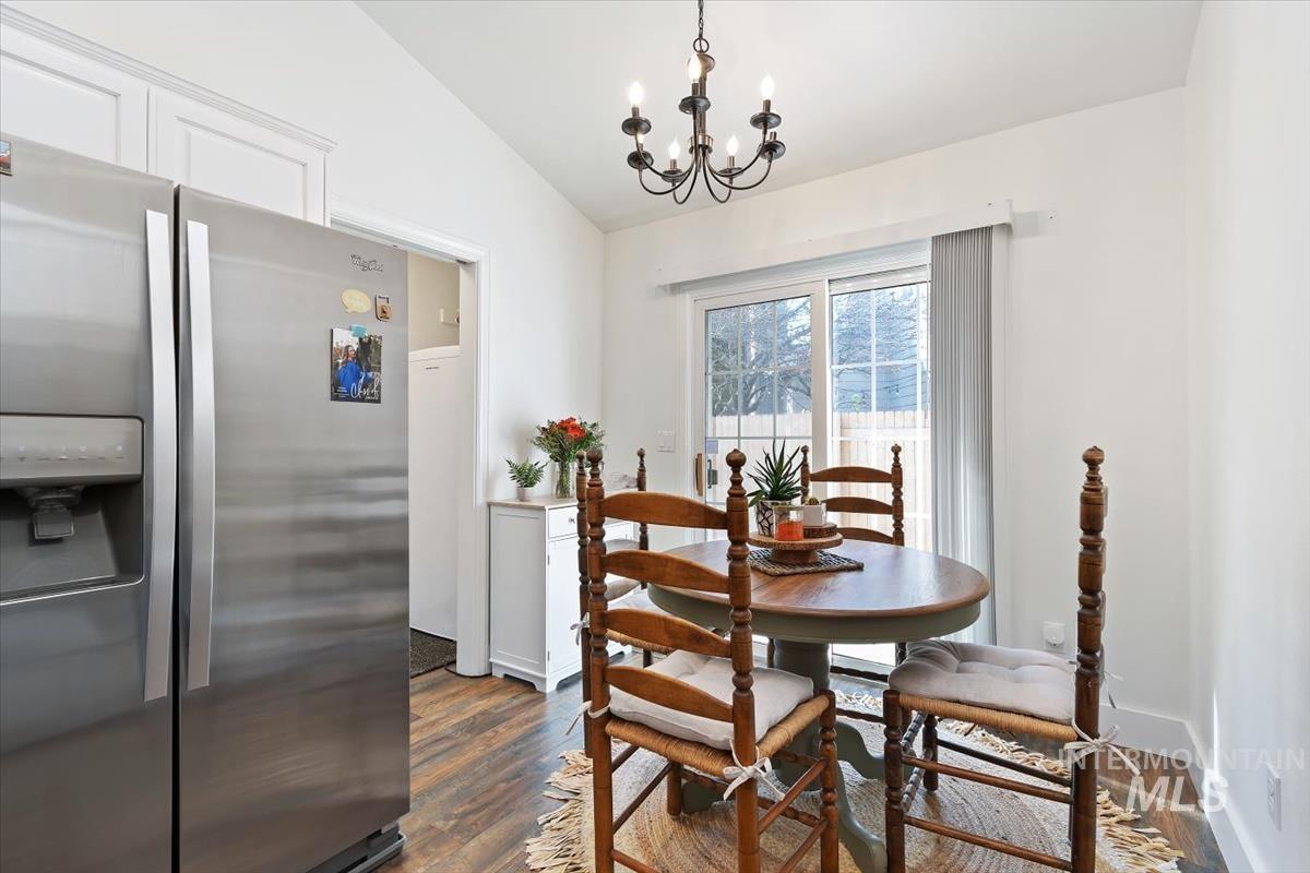 Dining area with vaulted ceiling, dark wood-type flooring, and a chandelier