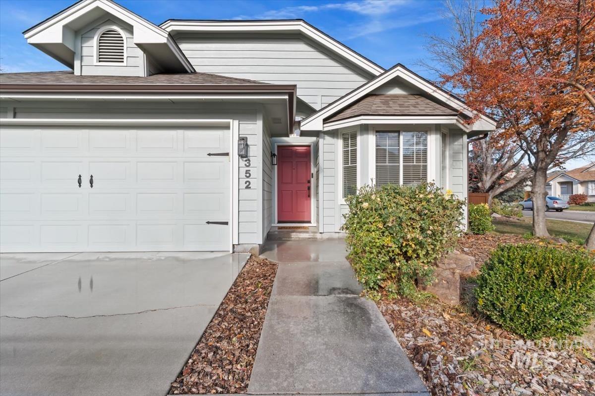 View of front of house with concrete driveway, roof with shingles, and an attached garage
