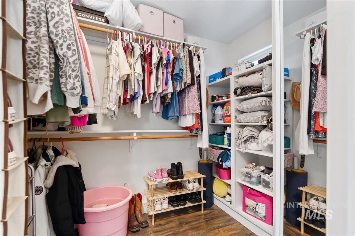 Walk in closet with dark wood-style flooring