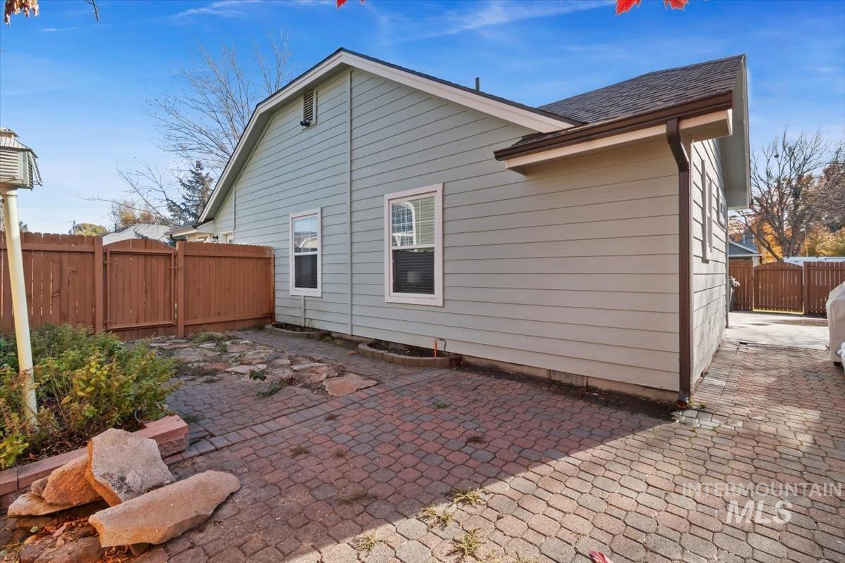 Rear view of house with a shingled roof and a patio area