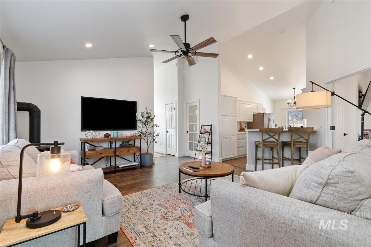 Living area featuring high vaulted ceiling, dark wood-style flooring, a wood stove, recessed lighting, and a ceiling fan