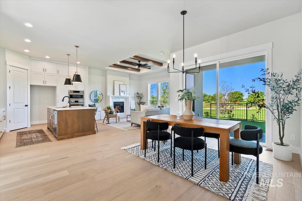 Dining area featuring light wood-type flooring, a fireplace, a chandelier, recessed lighting, and a ceiling fan