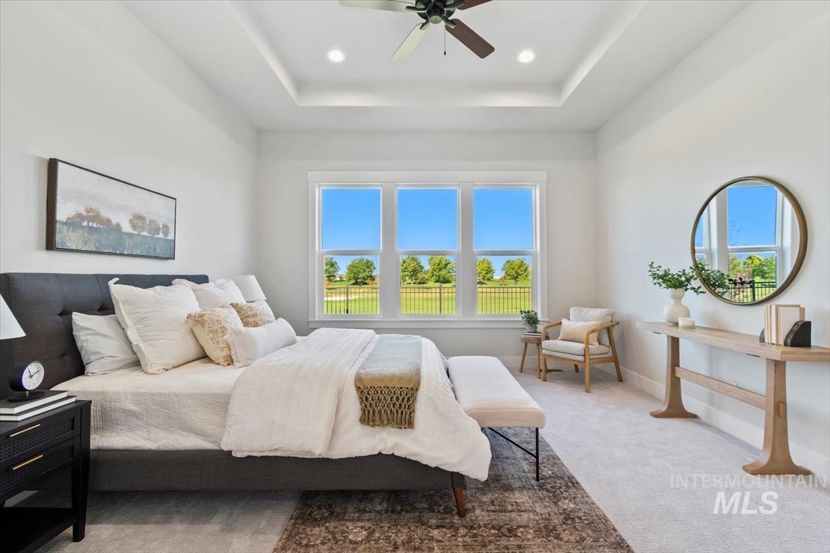 Bedroom with light colored carpet, a tray ceiling, a ceiling fan, and recessed lighting