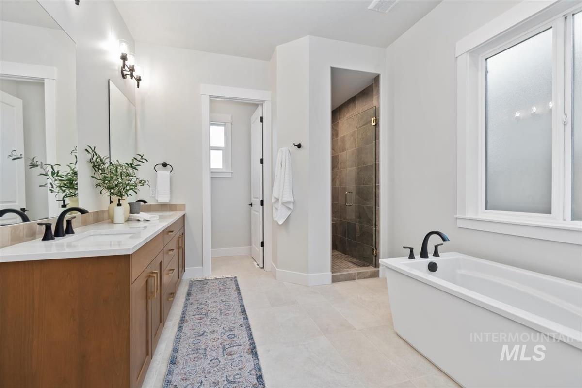 Bathroom with a freestanding tub, double vanity, a shower stall, and light tile patterned flooring