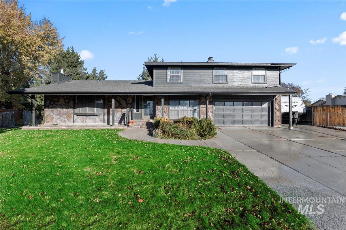 Traditional-style house featuring a chimney, a garage, driveway, a porch, and stone siding