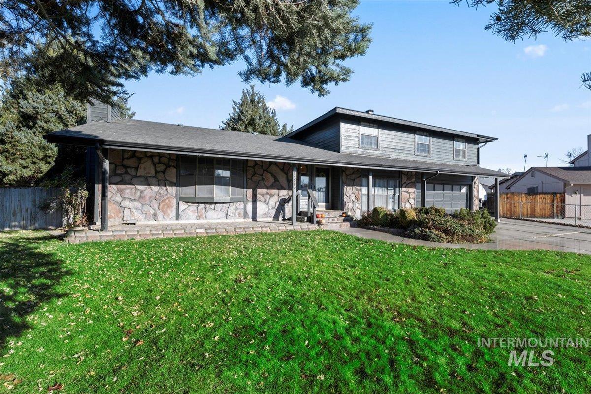 View of front of house featuring stone siding, covered porch, a chimney, a garage, and concrete driveway