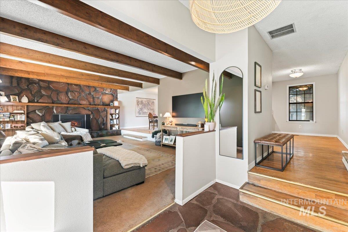 Living area with a textured ceiling, carpet, a fireplace, and beamed ceiling