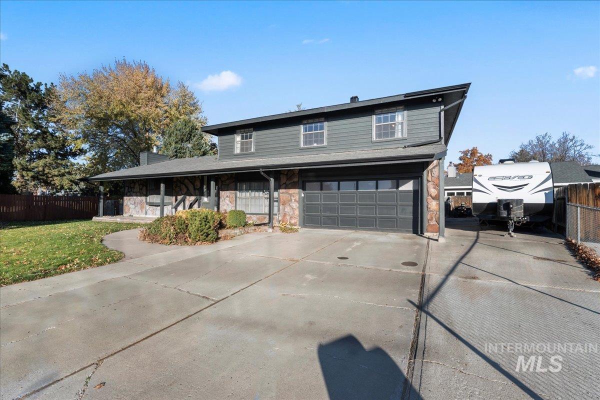 View of front facade with stone siding, concrete driveway, an attached garage, and a chimney