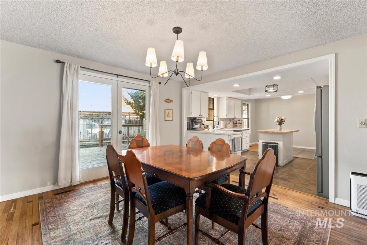 Dining room with light wood-type flooring, plenty of natural light, a chandelier, a textured ceiling, and recessed lighting