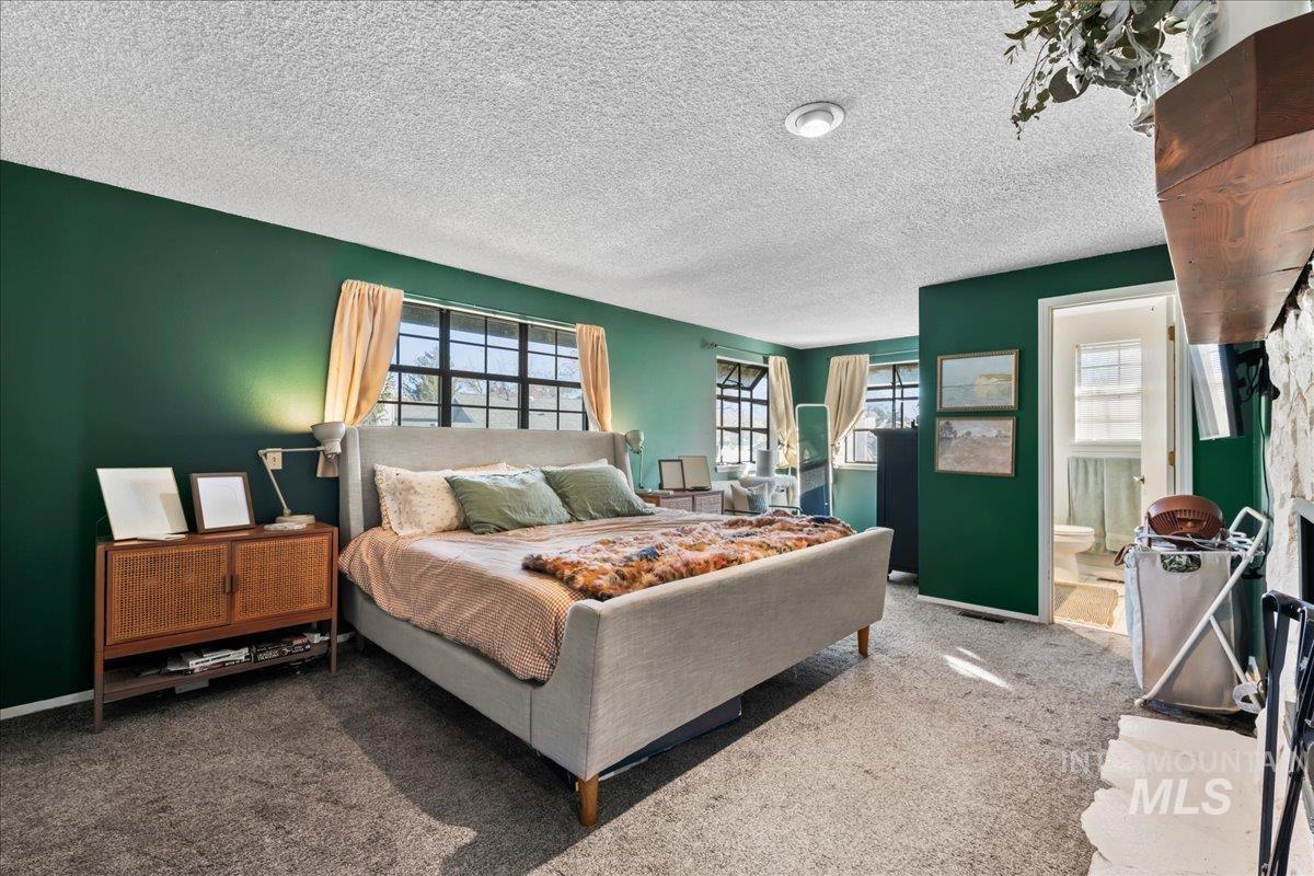 Bedroom featuring carpet flooring, a textured ceiling, and ensuite bath