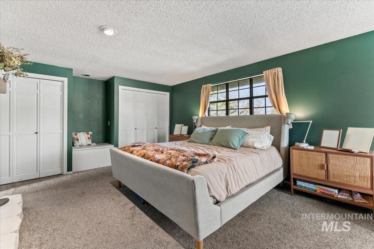 Bedroom featuring two closets, carpet flooring, and a textured ceiling