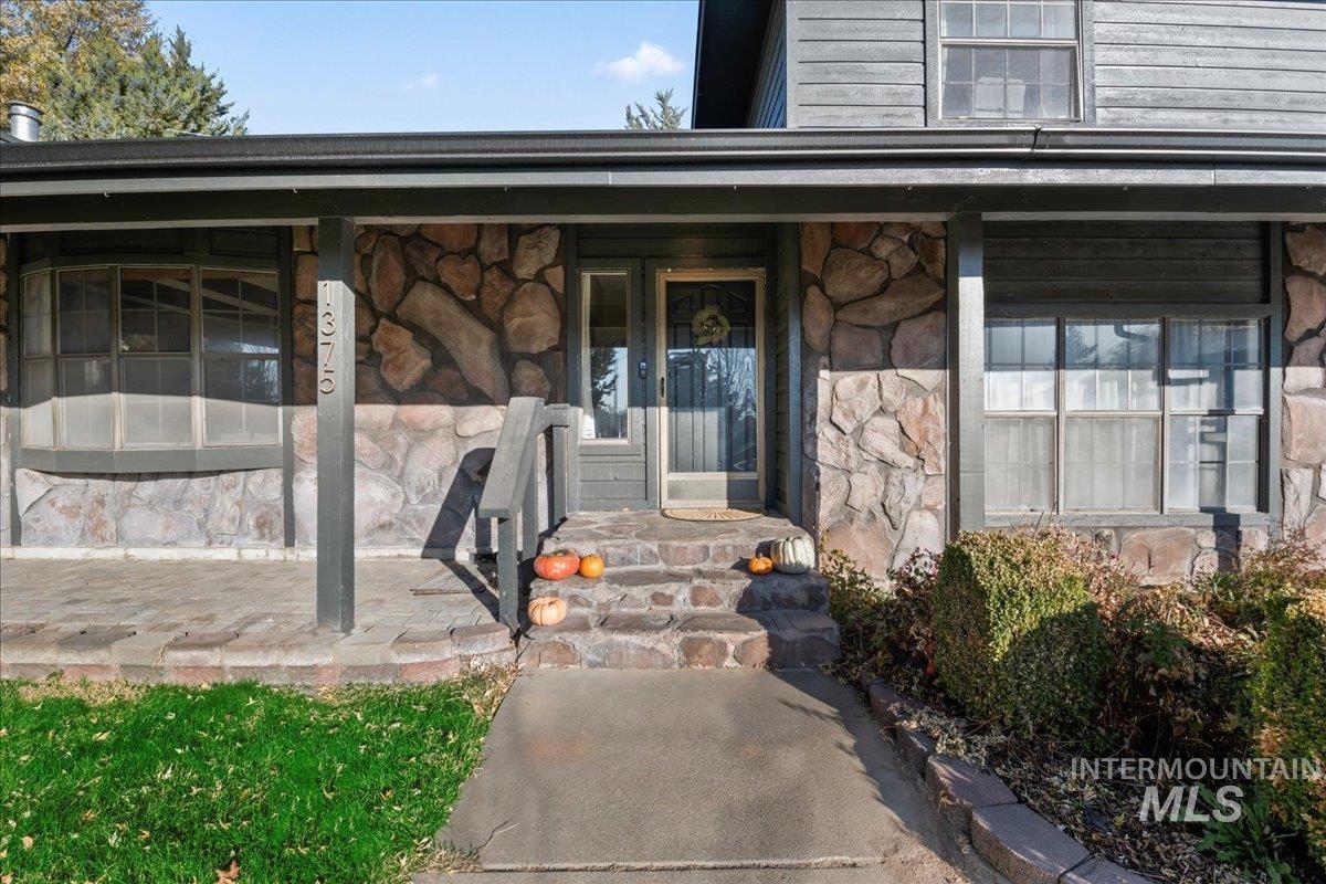 View of exterior entry featuring stone siding and covered porch