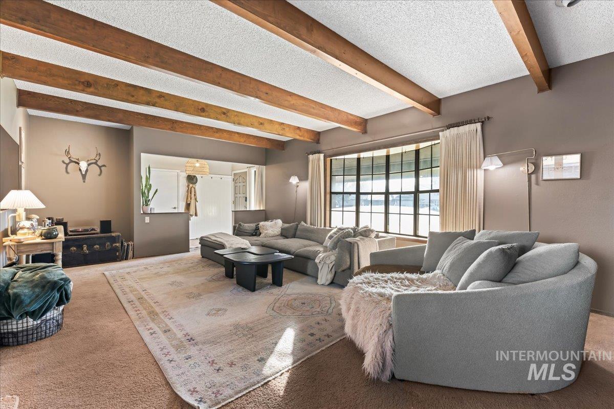 Carpeted living area with beamed ceiling and a textured ceiling