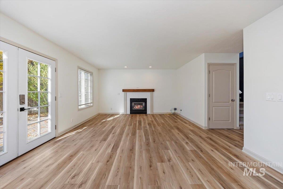 Unfurnished living room featuring french doors, a glass covered fireplace, and light wood finished floors