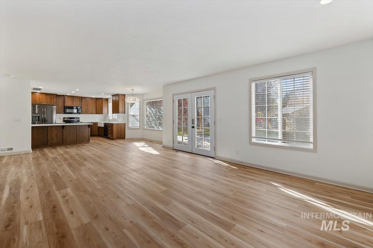 Unfurnished living room with light wood-style floors, french doors, and recessed lighting