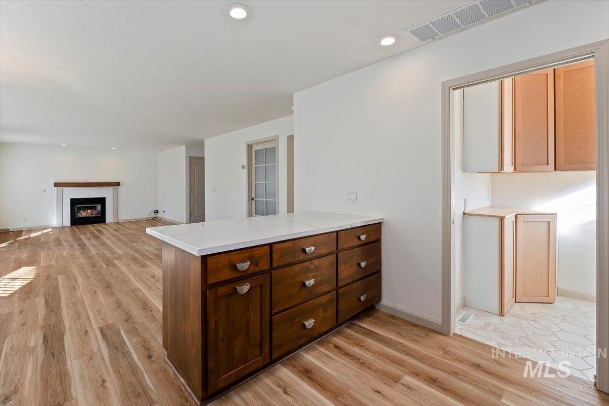 Kitchen with light wood-type flooring, a glass covered fireplace, a peninsula, recessed lighting, and open floor plan